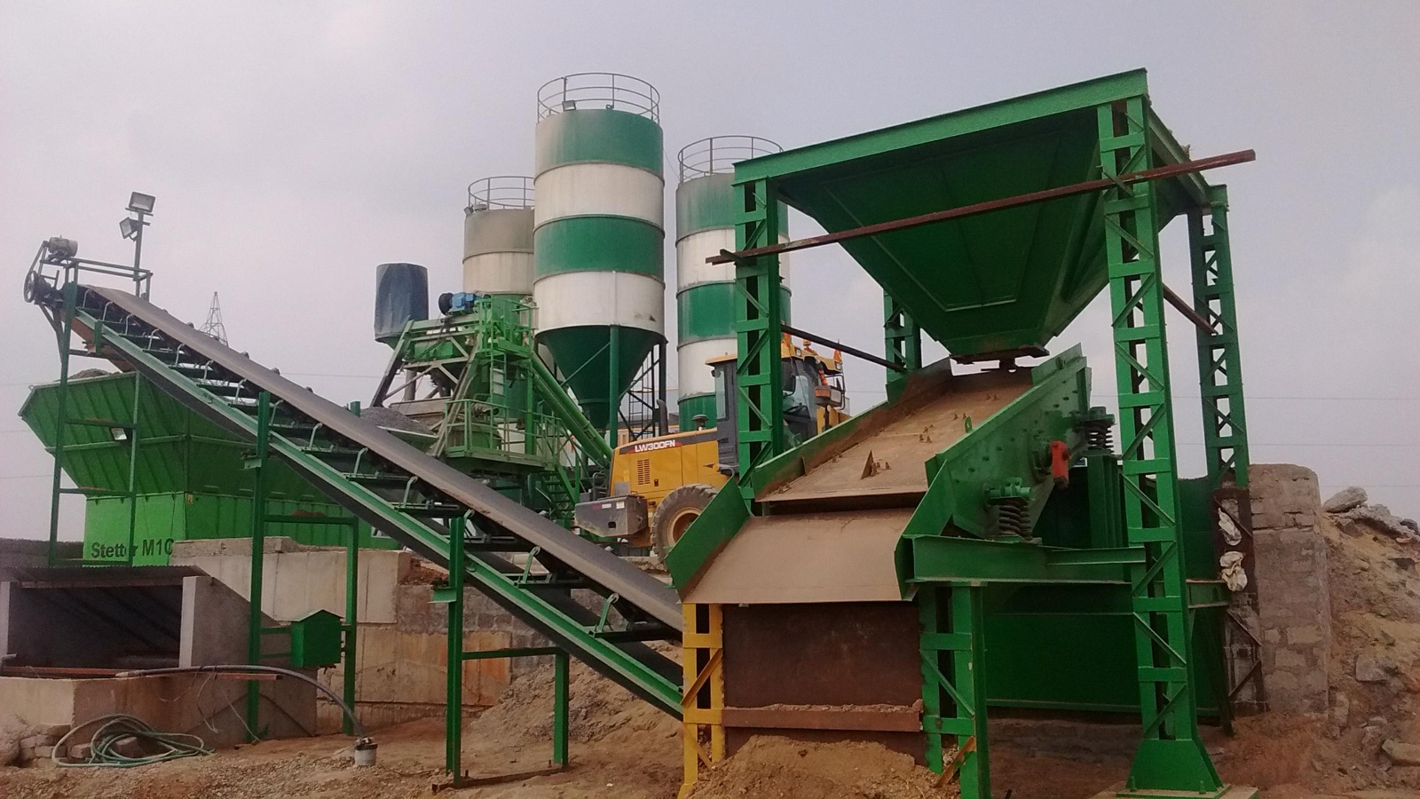 Dedicated on-site batching plant — silos, conveyor and wheel loader in operation